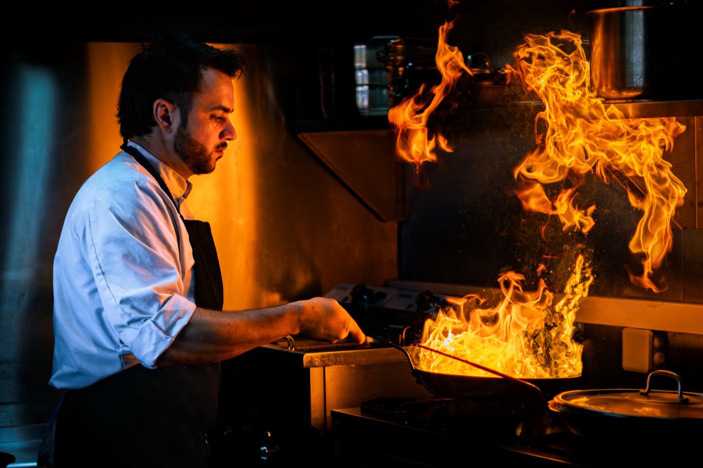 Chef cooking with flames in a restaurant kitchen